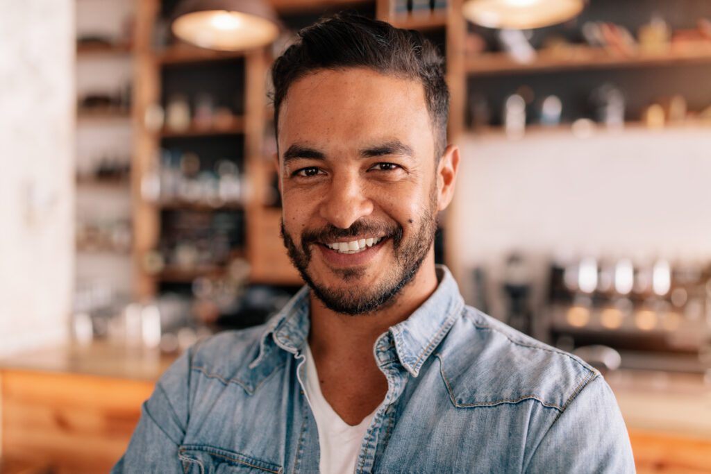 Close up portrait of handsome young man standing in a cafe. Smiling young caucasian male in a coffee shop.