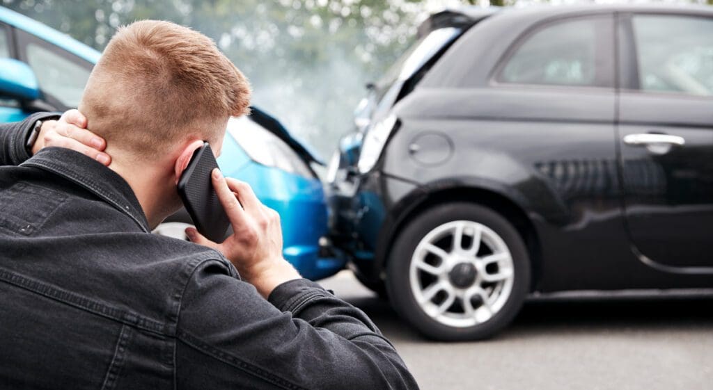 Young Male Motorist Involved In Car Accident Calling Insurance Company Or Recovery Service