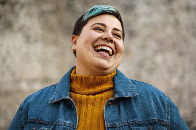 A Young Woman with Blue Streak in Hair Smiles Showing Her Teeth