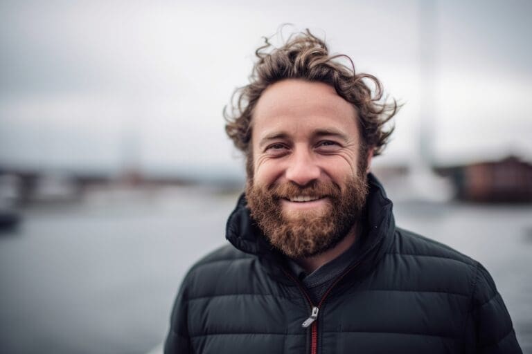 A Cheerful Man In His 30s Against A Dramatic Sailboat Race On A Windy Day Background