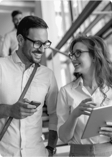 Two people in a business setting wearing glasses discussing content on a tablet